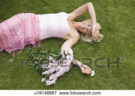 Stock Photo - Relaxed woman lying on grass . Fotosearch