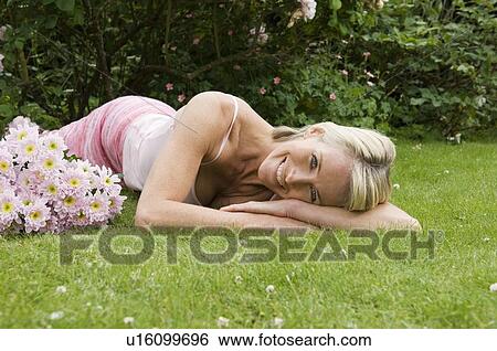Woman lying on grass with flowers View Large Photo Image Stock Photograph - Woman lying on grass with flowers. Fotosearch