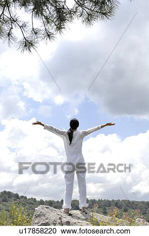Stock Image - Woman opening her arms against sky. Fotosearch