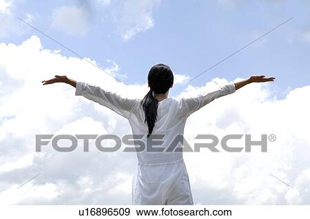 Stock Photo - Woman opening her arms against sky. Fotosearch