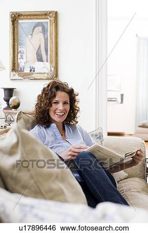 Woman reading a book sitting on a couch View Large Photo Image Stock Photograph - Woman reading a book sitting on a couch. Fotosearch