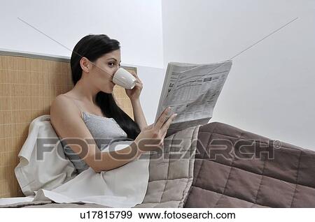 Stock Photo - Woman reading paper in her bed. Fotosearch