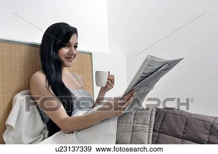 Woman reading paper in her bed View Large Photo Image Stock Photo - Woman reading paper in her bed. Fotosearch