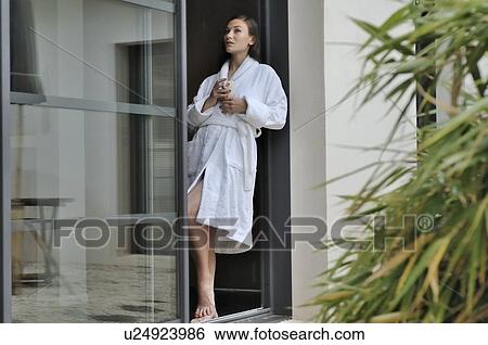 Stock Photograph - Woman relaxing by door with cup. Fotosearch