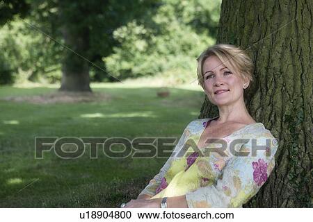 Women sitting by tree View Large Photo Image Stock Image - Women sitting by tree. Fotosearch