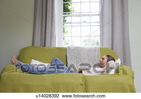 Young woman lying on couch View Large Photo Image Stock Image - Young woman lying on couch. Fotosearch