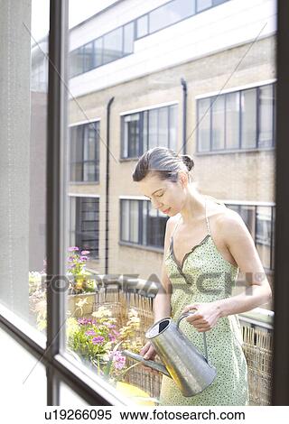 Woman on balcony watering flowers View Large Photo Image Stock Photography - Woman on balcony watering flowers. Fotosearch