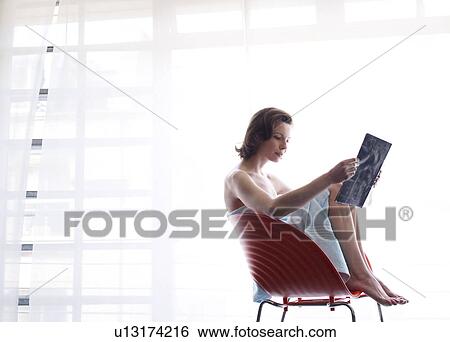 Stock Photograph - Woman sitting at window reading. Fotosearch