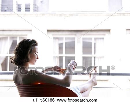 Woman sitting at window with a drink View Large Photo Image Stock Photograph - Woman sitting at window with a drink. Fotosearch