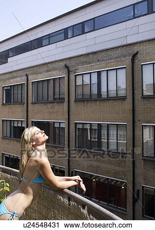 Woman sunbathing on city balcony View Large Photo Image Stock Image - Woman sunbathing on city balcony. Fotosearch