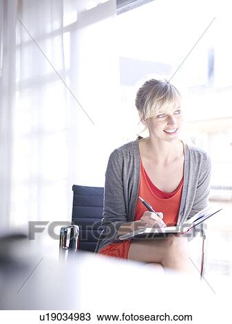 Stock Image - Woman writing at home office . Fotosearch
