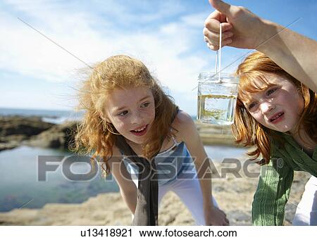2 girls looking at fish in jar by sea View Large Photo Image Stock Image - 2 girls looking at fish in jar by sea. Fotosearch