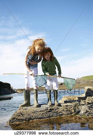 2 girls looking in nets at rock pool View Large Photo Image Stock Photo - 2 girls looking in nets at rock pool. Fotosearch