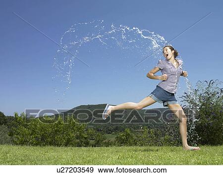 Stock Photo - Girl running through arc of water. Fotosearch