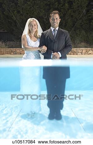 Picture - Wedding couple standing in pool. Fotosearch
