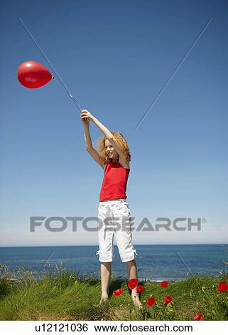 Young girl standing with red balloon View Large Photo Image Stock Photograph - Young girl standing with red balloon. Fotosearch