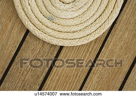 Close-up of a curled up rope on the deck of a sailboat View Large Photo Image Stock Photo - Close-up of a curled up rope on the deck of a sailboat. Fotosearch