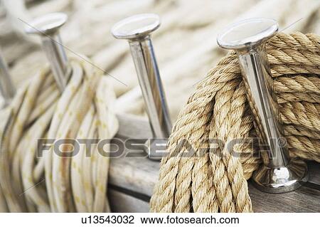 Stock Image - Close-up of pegs and ropes on the deck of a sailboat. Fotosearch