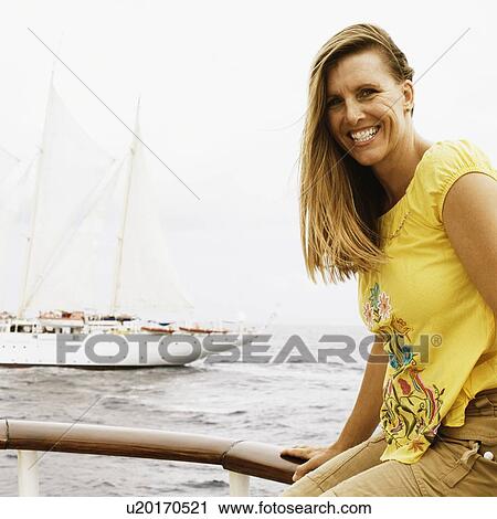 Portrait of a mid adult woman sitting on a railing and smiling View Large Photo Image Stock Image - Portrait of a mid adult woman sitting on a railing and smiling. Fotosearch