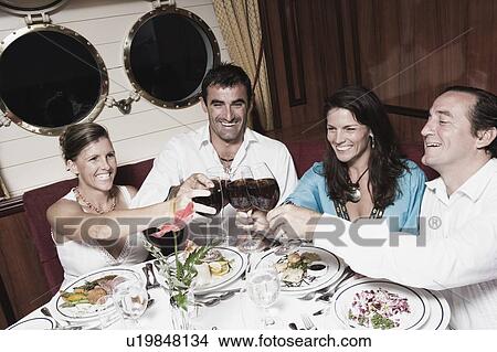 Two mid adult couples toasting with wine glasses and smiling View Large Photo Image Picture - Two mid adult couples toasting with wine glasses and smiling. Fotosearch