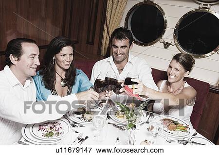 Two mid adult couples toasting with wine glasses and smiling View Large Photo Image Stock Photo - Two mid adult couples toasting with wine glasses and smiling. Fotosearch