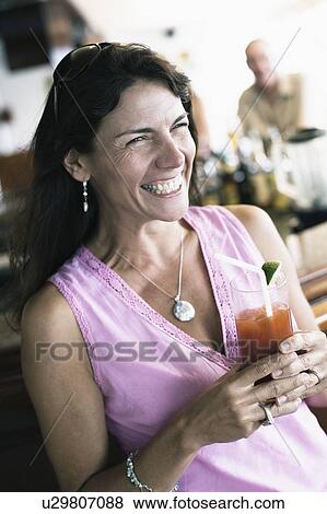 Stock Photo - Close-up of a mid adult woman holding a glass of juice and smiling. Fotosearch