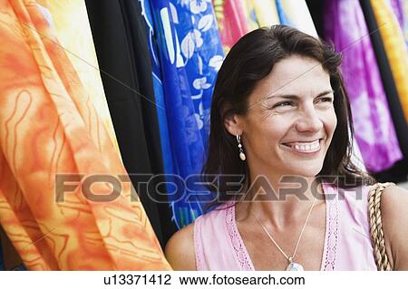 Close-up of a mid adult woman smiling at a clothing store View Large Photo Image Stock Image - Close-up of a mid adult woman smiling at a clothing store. Fotosearch