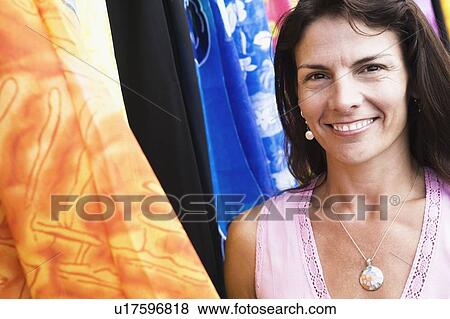 Stock Photo - Close-up of a mid adult woman smiling at a clothing store. Fotosearch
