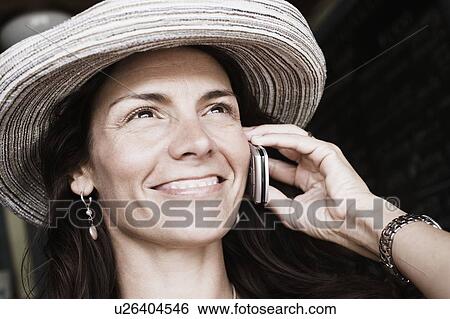 Close-up of a mid adult woman talking on a mobile phone and smiling View Large Photo Image Stock Photograph - Close-up of a mid adult woman talking on a mobile phone and smiling. Fotosearch