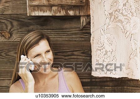 Close-up of a mid adult woman talking on a mobile phone and smiling View Large Photo Image Stock Photography - Close-up of a mid adult woman talking on a mobile phone and smiling. Fotosearch