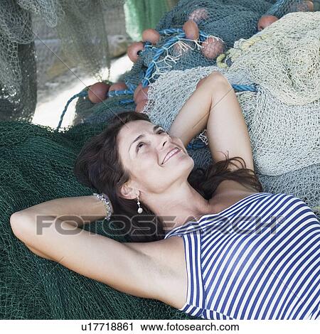 High angle view of a mid adult woman lying on commercial fishing nets and smiling View Large Photo Image Stock Image - High angle view of a mid adult woman lying on commercial fishing nets and smiling. Fotosearch