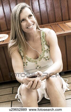 Mid adult woman listening to music and smiling View Large Photo Image Stock Photo - Mid adult woman listening to music and smiling. Fotosearch