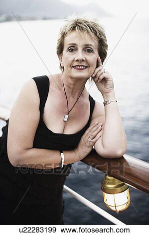 Portrait of a mature woman leaning against a railing and smiling View Large Photo Image Stock Photo - Portrait of a mature woman leaning against a railing and smiling. Fotosearch