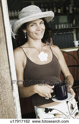 Stock Image - Portrait of a mid adult woman holding a cup of coffee. Fotosearch