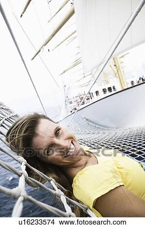 Portrait of a mid adult woman lying on the net of a sailing ship and smiling View Large Photo Image Picture - Portrait of a mid adult woman lying on the net of a sailing ship and smiling. Fotosearch