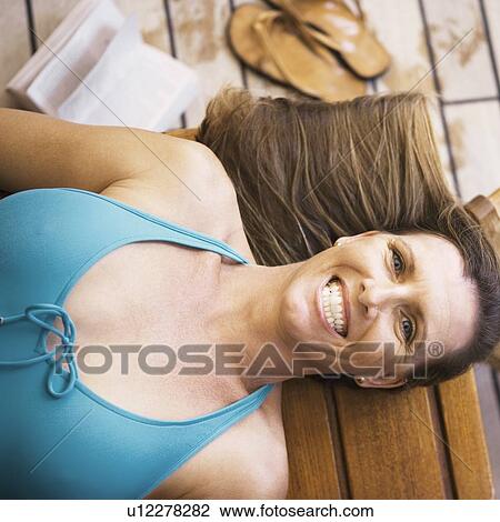 Portrait of a mid adult woman lying on a bench and smiling View Large Photo Image Stock Image - Portrait of a mid adult woman lying on a bench and smiling. Fotosearch