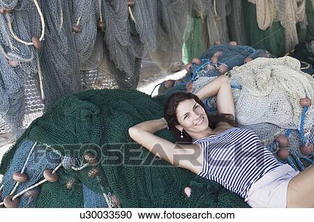 Portrait of a mid adult woman lying on commercial fishing nets and smiling View Large Photo Image Stock Image - Portrait of a mid adult woman lying on commercial fishing nets and smiling. Fotosearch
