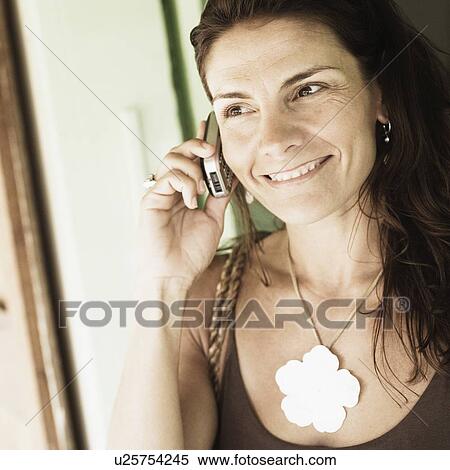 Close-up of a mid adult woman talking on a mobile phone and smiling View Large Photo Image Stock Photography - Close-up of a mid adult woman talking on a mobile phone and smiling. Fotosearch