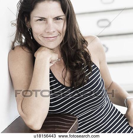 Portrait of a mid adult woman smirking with her hand on her chin View Large Photo Image Stock Image - Portrait of a mid adult woman smirking with her hand on her chin. Fotosearch