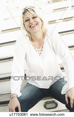 Portrait of a young woman sitting on steps with her hands on her knees and laughing View Large Photo Image Stock Image - Portrait of a young woman sitting on steps with her hands on her knees and laughing. Fotosearch