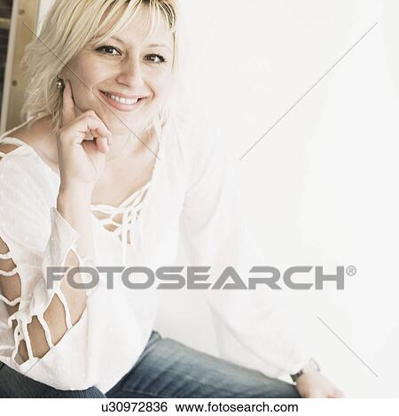 Portrait of a young woman smiling with her hands on her chin View Large Photo Image Stock Photograph - Portrait of a young woman smiling with her hands on her chin. Fotosearch