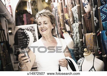 Close-up of a mature woman holding a mobile phone and smiling View Large Photo Image Stock Photo - Close-up of a mature woman holding a mobile phone and smiling. Fotosearch