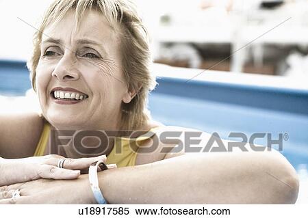 Close-up of a mature woman leaning on the ledge of a swimming pool and smiling View Large Photo Image Stock Photography - Close-up of a mature woman leaning on the ledge of a swimming pool and smiling. Fotosearch