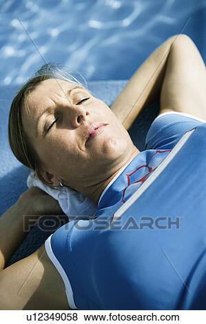 Close-up of a mid adult woman lying on the ledge of a swimming pool View Large Photo Image Stock Photo - Close-up of a mid adult woman lying on the ledge of a swimming pool. Fotosearch