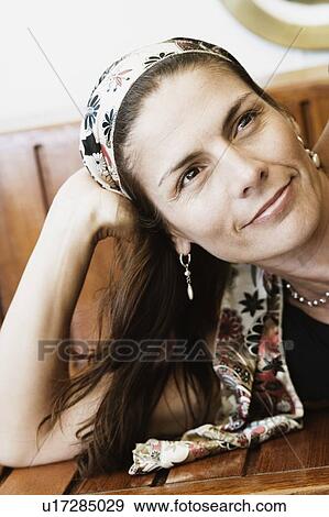Close-up of a mid adult woman lying on a bench and smiling View Large Photo Image Stock Photo - Close-up of a mid adult woman lying on a bench and smiling. Fotosearch