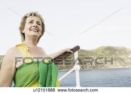 Stock Photo - Mature woman standing at the railing of a sailing ship and smiling. Fotosearch