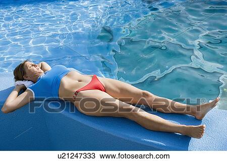 Mid adult woman lying on the ledge of a swimming pool View Large Photo Image Stock Image - Mid adult woman lying on the ledge of a swimming pool. Fotosearch