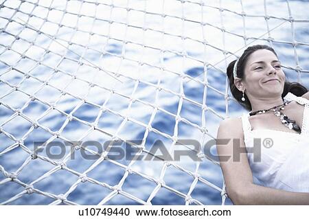 Mid adult woman lying on the net of a ship and smiling View Large Photo Image Stock Image - Mid adult woman lying on the net of a ship and smiling. Fotosearch