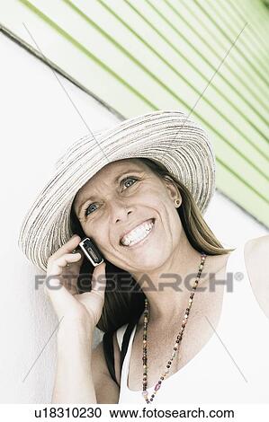 Mid adult woman talking on a mobile phone and smiling View Large Photo Image Stock Image - Mid adult woman talking on a mobile phone and smiling. Fotosearch