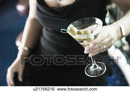 Mid section view of a woman holding a glass of cocktail View Large Photo Image Stock Photograph - Mid section view of a woman holding a glass of cocktail. Fotosearch